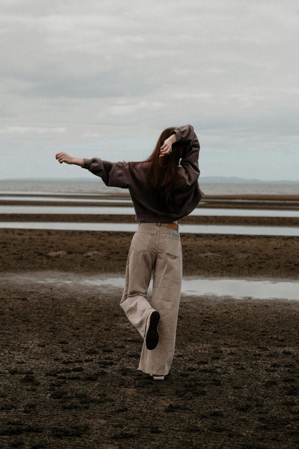 a woman standing on a beach with her arms outstretched